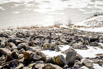 Obraz premium View of large rocks with snow on top leading to a view of the Loyalhanna reservoir. Located in Western Pennsylvania.