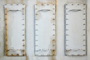 Three metal hatches plates on compressor for revision close-up with oil stains painted with gray paint bolted with studs and nuts background with copyspace.