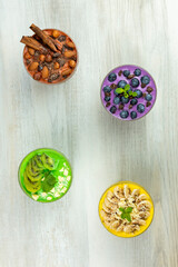Fototapeta na wymiar Smoothies or puddings with kiwi, bannas, blueberries and chocolate with almonds and hazelnuts in a crystal bowls.Top view image