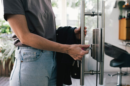 Midsection of female hair dresser opening lock of salon