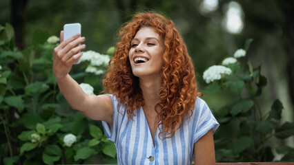 Fototapeta premium glad redhead woman taking selfie in green park.