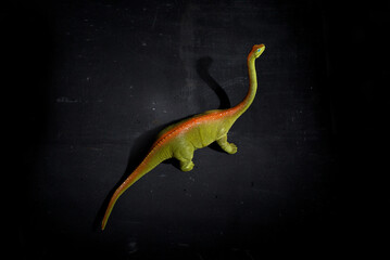 Plastic toy dinosaur in spotlight on dark background