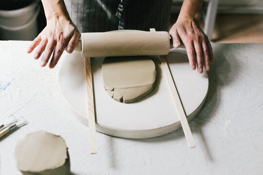 Female owner rolling clay at table in ceramics store