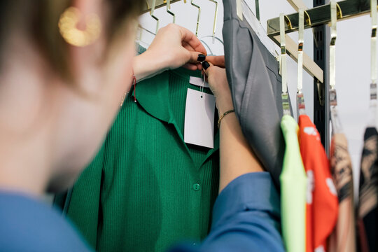 Female owner tying price tag on clothes in store