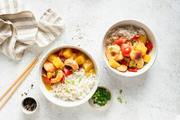 White rice in bowl with pineapple shrimp curry on grey concrete table background, top view