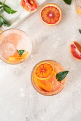 Cold refreshing drink with tonic, blood Sicilian oranges and ice, grey background. Cocktail with tonic and oranges.