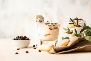 Traditional Italian dessert tiramisu in glass. Coffee flavored portion dessert made of savoiardi and mascarpone decorated with cocoa powder.