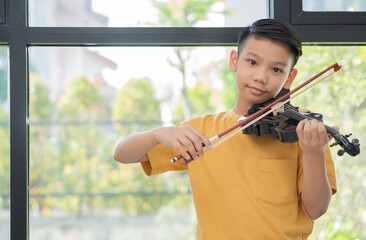 A Little Asian kid playing and practice violin musical string instrument against in home, Concept of Musical education, Inspiration, Teenager art school student.