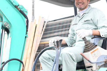 工事現場で重機に乗る作業員の男性（カメラ目線）