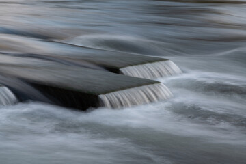 Long time exposure of water with strong current forming 3 littel cascade waterfalls. Concrete cubes...