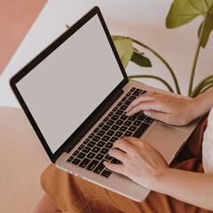 Fototapeta premium Young woman working on laptop computer with copy space. Comfortable home office workspace interior design. Work at home