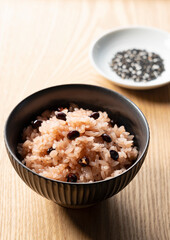 Red rice and sesame salt on a wooden table.