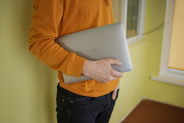 The guy in orange clothes holds a laptop in his hands