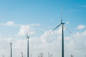 Windmills during bright summer day with blue sky, clean and renewable energy concept.