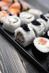 Sushi with rolls on the black plate. Fresh shushi.