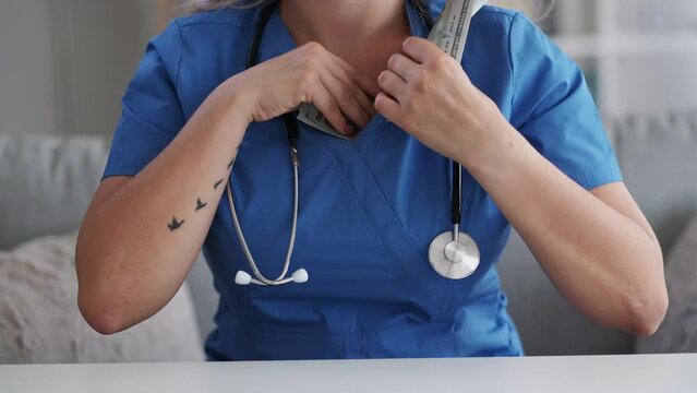 Health tax. Medical insurance. Illegal income. Unrecognizable dishonest sneaky female doctor counting stealing money hiding 100 bill American us dollar cash banknote.