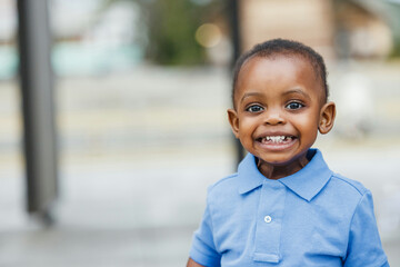 A cute one year old toddler almost preschool age African-American boy with big eyes smiling and...