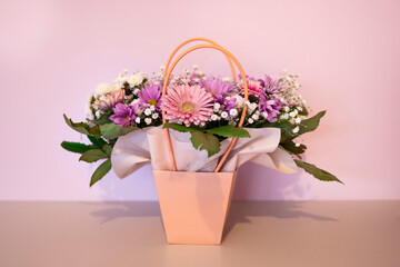 A composition of flowers in a festive box stands on the stairs with lighting. A gift for a beloved woman