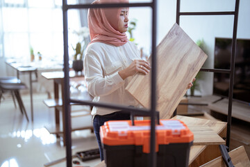 Fototapeta na wymiar muslim woman assembling new furniture at home