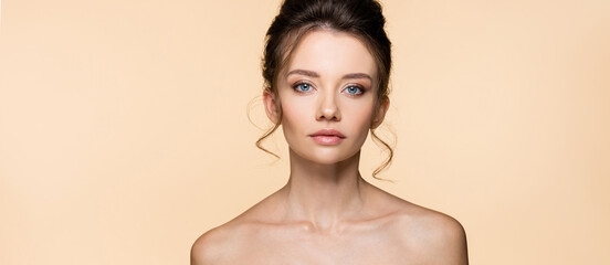 Portrait of brunette model with naked shoulders isolated on beige, banner.