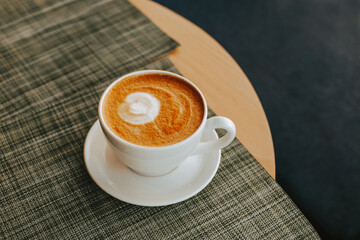 A large white cup of freshly brewed cappuccino on almond milk. Aromatic coffee on vegetable milk in a coffee shop.