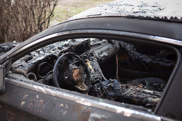 Burnt car interior close-up. Steering wheel and dashboard. Car after the fire. Car wreck burned by...