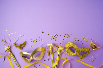 Flat lay composition for carnival or mardi gras background with golden carnival masks on violet...
