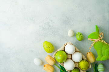 Easter holiday concept with Easter eggs and tulip flowers decor on gray background. Top view, flat lay