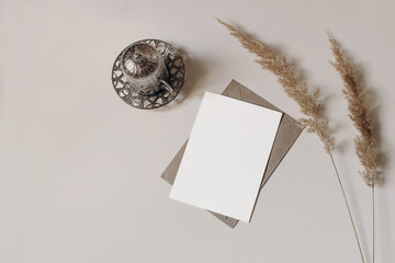 Silver Turkish decorative cup with tea. Dry grass. On beige table. Greeting card mockup for Muslim community holy month Ramadan Kareem or boho wedding. Festive background, lat lay, top view. © tabitazn