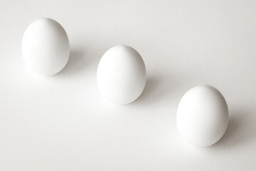 Three white eggs on a white background