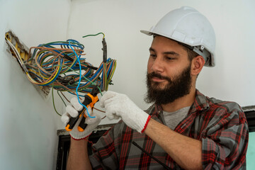Electrician contractors wear engineer helmets for safety, use screwdrivers to inspect ceiling wires...