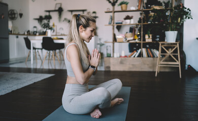 Fototapeta na wymiar Girl practicing yoga on fitness mat at home