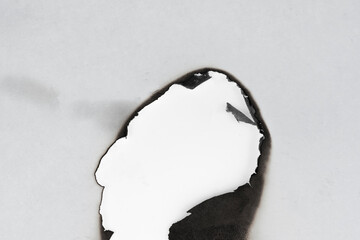 Burnt hole isolated on white paper. burns borders paper close up