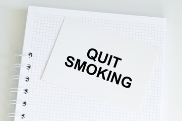 Quit Smoking text on a white card against the background of a notepad that is on the table