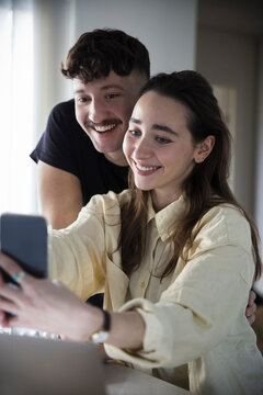 Happy couple taking selfie on smart phone at home