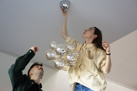 Woman hanging chandelier with boyfriend while moving in new house