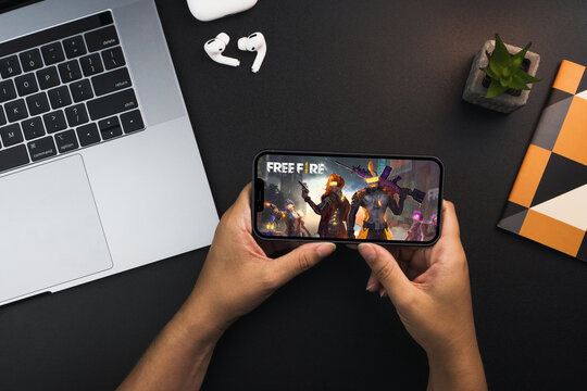 Girl holding a smartphone with Free Fire game app on the screen on black background table. Office environment. Rio de Janeiro, RJ, Brazil. February 2022