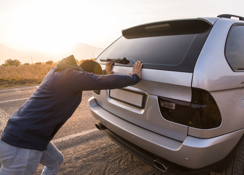 The man pushes the broken car