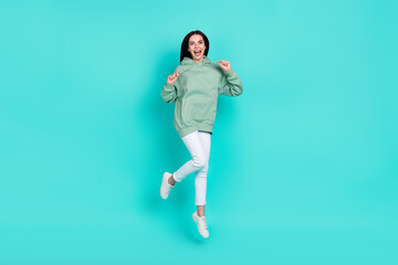 Fototapeta na wymiar Full size photo of impressed millennial brunette lady jump wear hoodie pants footwear isolated on teal background