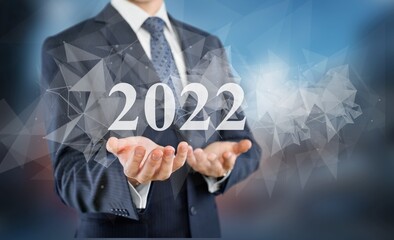Businessman in a suit chooses 2022 on a background. new year start ideas