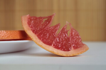 A red slice of grapefruit on a wooden table.