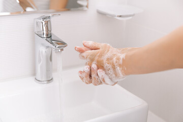 Washing hands under the flowing water tap. Washing hands rubbing with soap for corona virus prevention, hygiene to stop spreading corona virus in or public wash room. Hygiene concept hand detail