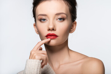 Young model with naked shoulder touching red lips isolated on white.