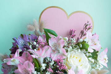 Delicate bouquet pink lilies, white roses, gypsophila. Turquoise background. Pink Heart, copy space