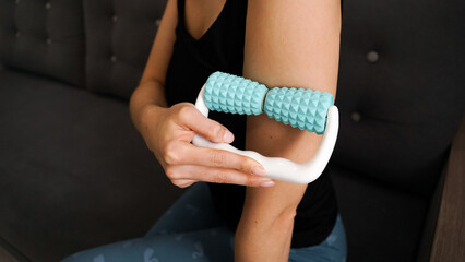 Woman massaging herself with body roller at home. Massage after sports. Health concept
