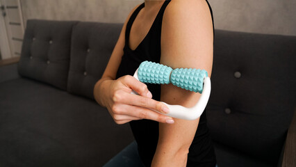Woman massaging herself with body roller at home. Massage after sports. Health concept