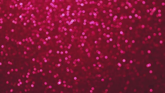 Bokeh background of vibrant pink deep magenta colors. Slow changing tiny circles on dark back. Holidays Valentine's day concept with copy space