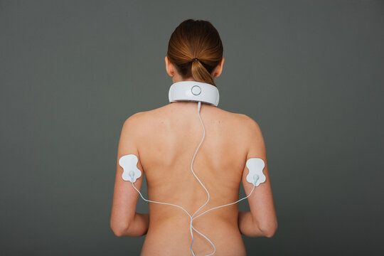 White woman with neck and hand massager. Massager with electrodes on the hands.