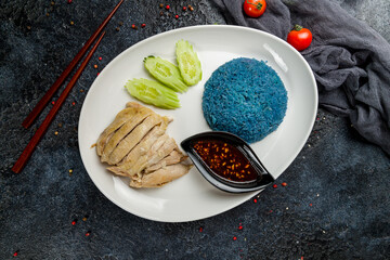 boiled chicken with rice and chili sauce with cucumbers on plate on dark stone table, Chinese cuisine