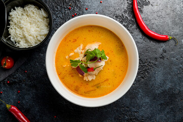 Tom Yam soup with chicken on bowl on dark stone table top view